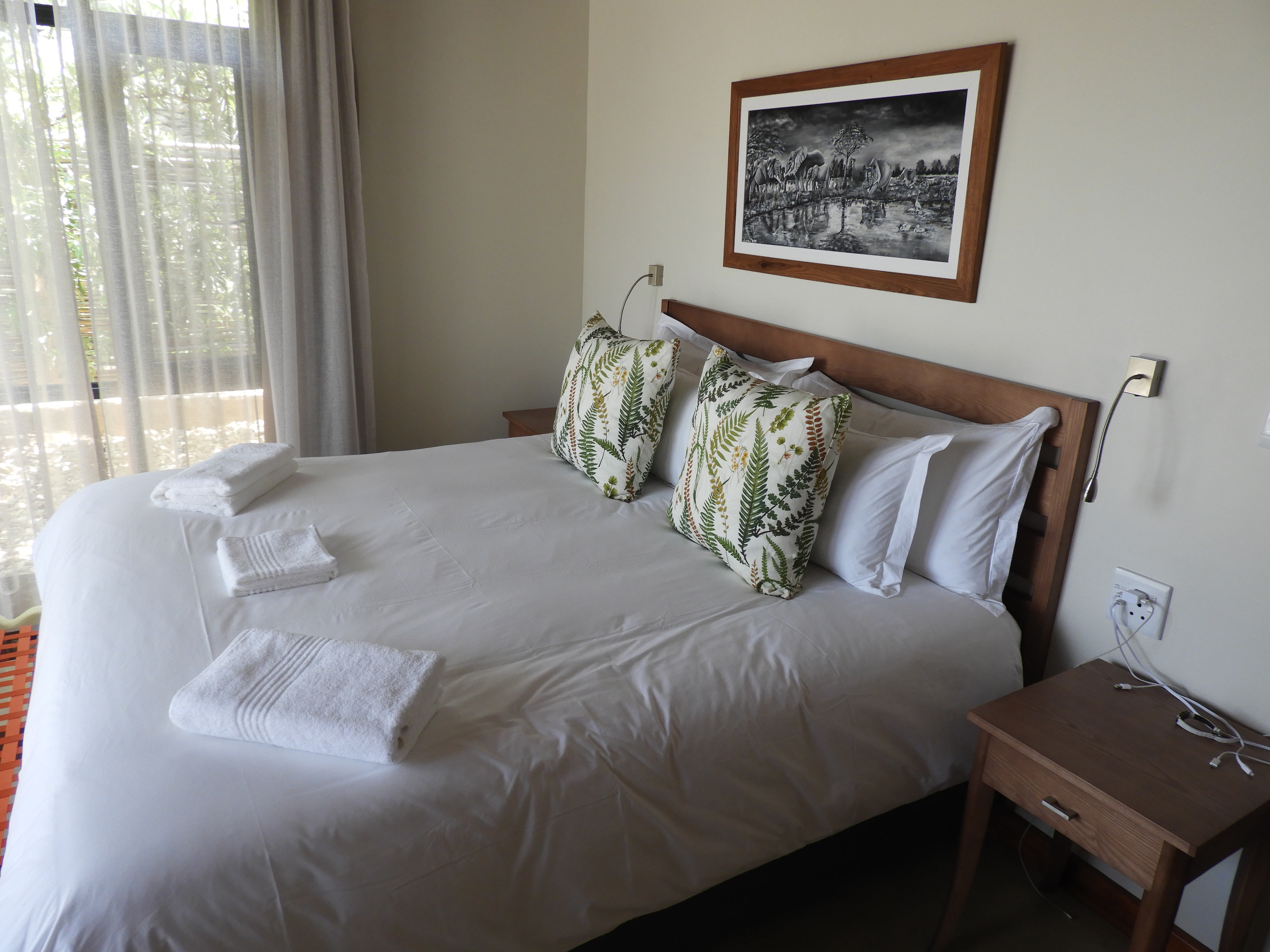 King bedroom with botanical cushions and beamed ceiling