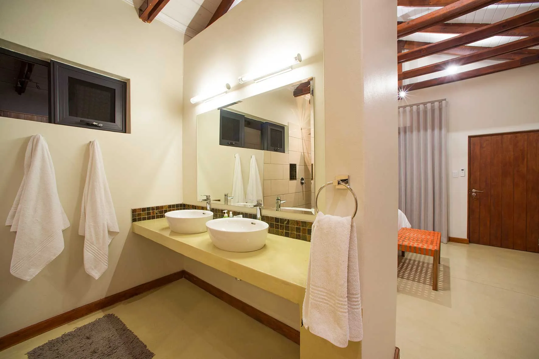 En-suite bathroom with twin basins and beamed ceiling