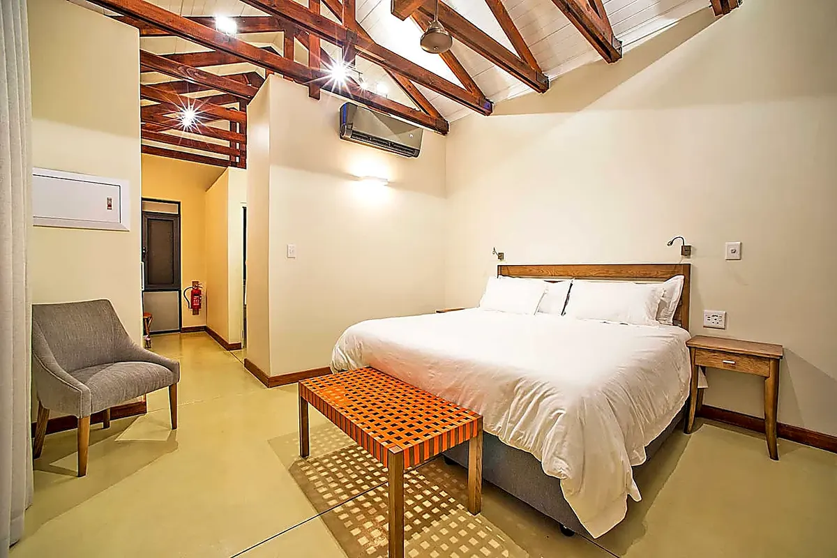 Bedroom with exposed timber rafters and crisp white linen