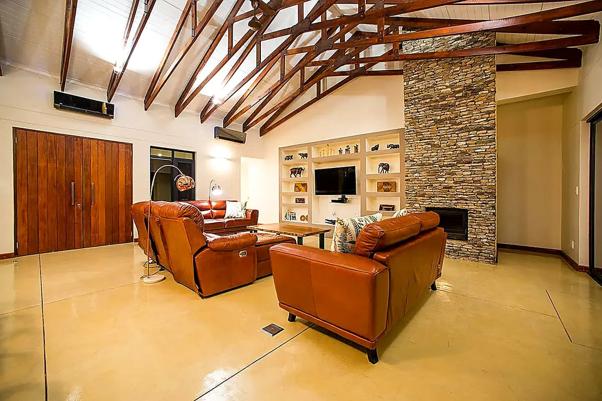 Lounge with leather sofas, stone fireplace and timber beam cathedral ceiling