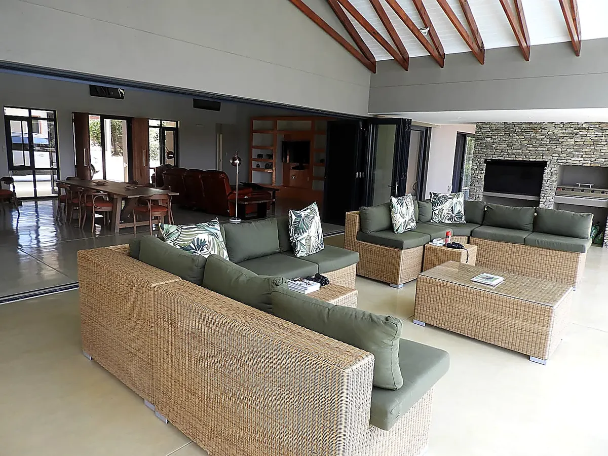 Open-plan outdoor seating area with wicker sofas and fireplace beyond