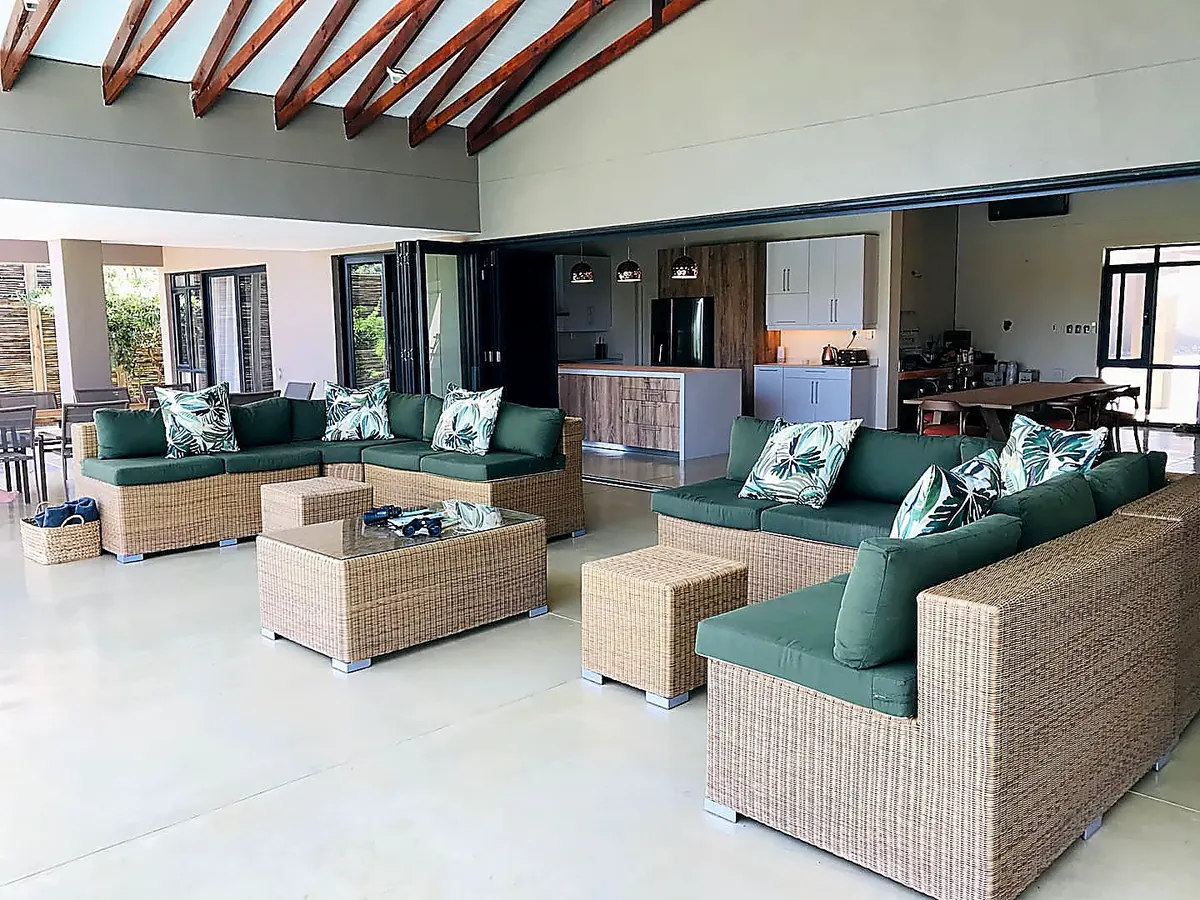 Open-plan outdoor seating area with wicker sofas and kitchen beyond