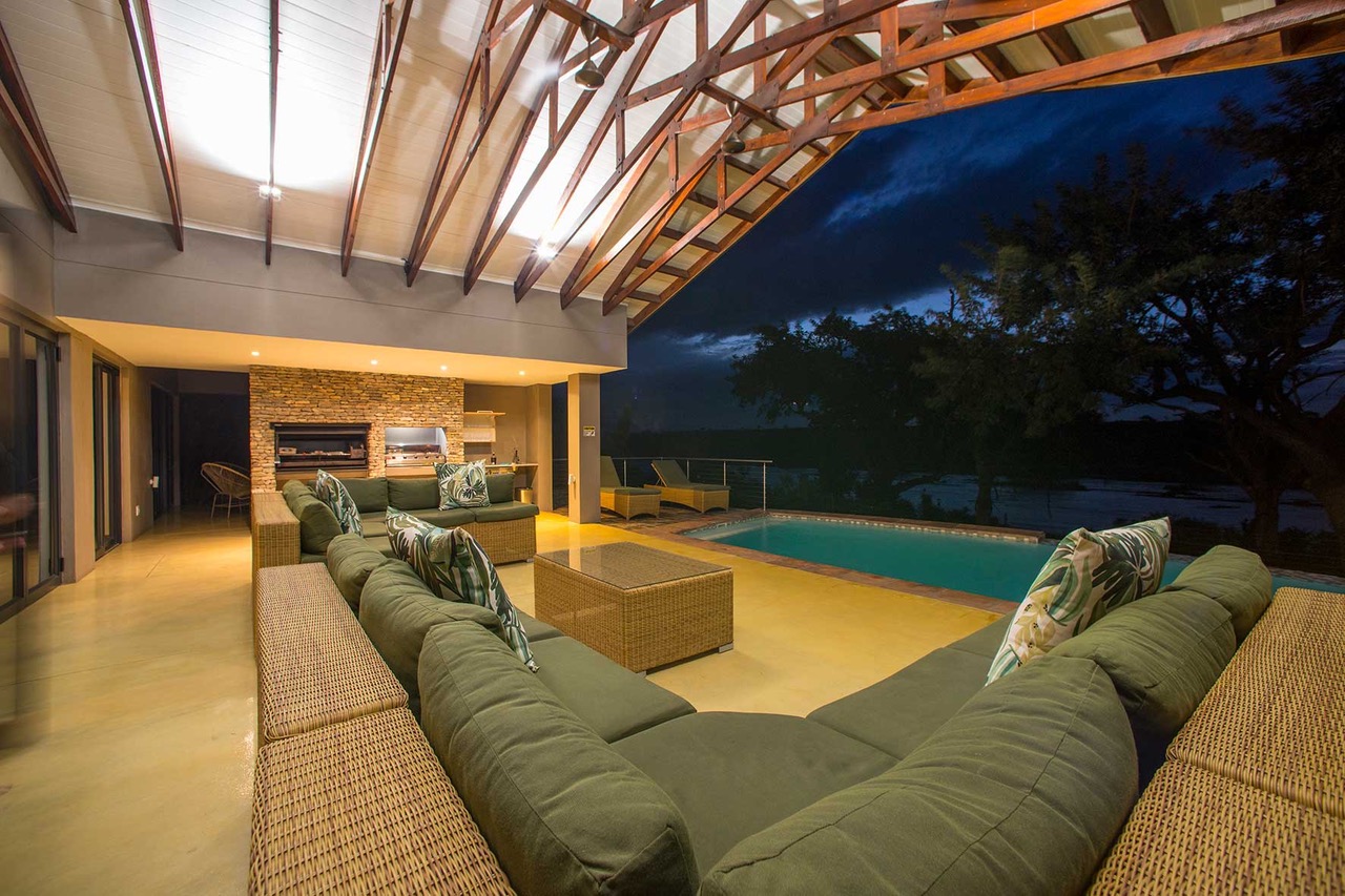 Stoep lounge at night with pool and bush beyond